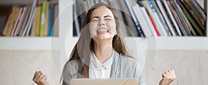 Happy woman sitting at workplace celebrating great opportunity at work