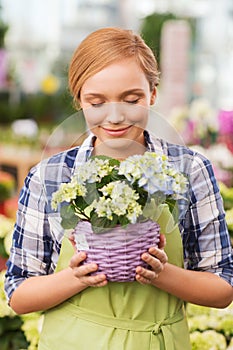 Happy woman smelling flowers in greenhouse
