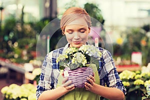 Happy woman smelling flowers in greenhouse