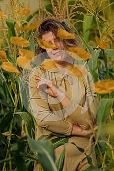 Happy woman with a smile on face. Happy pretty girl posing in the thickets of a corn field. Autumn leaves falling