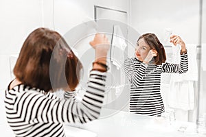 Happy woman smiling and drying her hair with hairdryer near the mirror in the bathroom