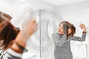 Happy woman smiling and drying her hair with hairdryer near the mirror in the bathroom