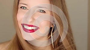 Happy woman smiling with perfect white teeth smile and posing in close-up portrait, female model with long hair wearing golden