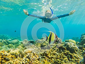 Happy woman in snorkeling mask dive underwater with tropical fishes in coral reef sea pool. Travel lifestyle, water