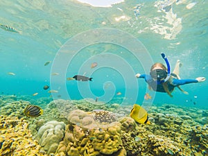 Happy woman in snorkeling mask dive underwater with tropical fishes in coral reef sea pool. Travel lifestyle, water