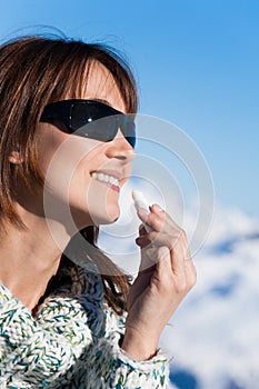 Happy Woman on the snow applying a protective cream