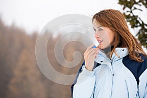 Happy Woman on the snow applying a protective cream