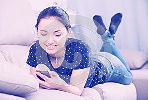 Happy woman on sofa with smartphone