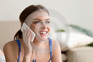 Happy woman speaking on mobile phone at home