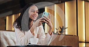 Happy woman speaking with smartphone, listening voice message. Girl use mobile voice control sitting in cafe, business
