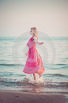 Happy woman is spinning and dancing on the beach on a Sunny day.