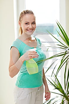 Happy woman in spraying houseplants at home
