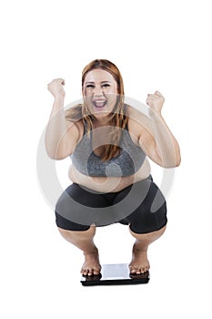 Happy woman squat on weight scale