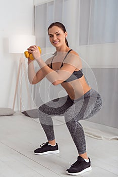 Happy woman squatting with hand weights