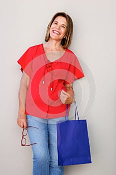 Happy woman standing against wall with shopping bag