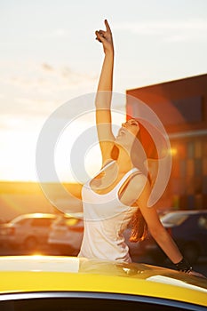 Happy young fashion woman by her car