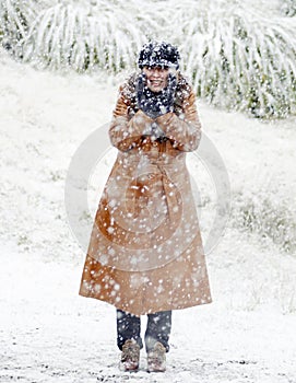 Happy woman standing in fresh falling white snow