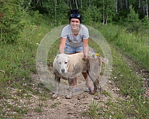 Happy woman standing with grimy dog in the woods.