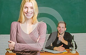 Happy woman standing hands crossed in classroom with teacher. Female student with schoolmaster at examination. High