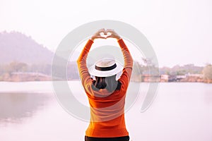 Happy woman standing and hands showing heart shape at sunset,Positive thinking,Free time,Back view