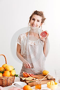 Happy woman standing indoors near table with a lot of citruses