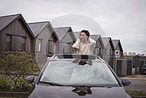 Happy Woman Standing out of Car Sunroof. Road Trip Joy. Carefree lifestyle