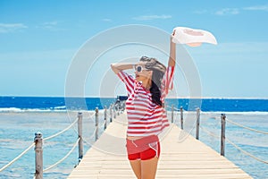 Happy woman standing on pier with big white hat