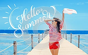 Happy woman standing on pier with big white hat and text Hello Summer. Calligraphy lettering