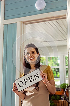 Happy woman standing on the porch of her shop.