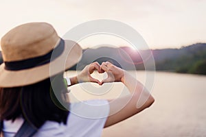 Happy woman standing and showing hands heart shape at sunset,Free time,Positive thinking