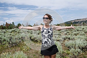 Happy woman stands in a field of high desert sagebrush and creosote bushes in rural Wyoming