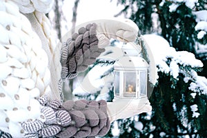 A happy woman stands with a lantern in her hands, a winter park with snow-covered trees