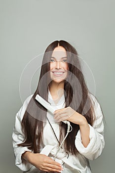 Happy woman straighten her hair on white background. Haircare concept photo