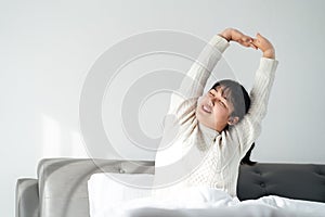 Happy Woman stretching her arms on the bed in the morning