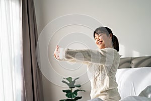 Happy Woman stretching her arms on the bed in the morning