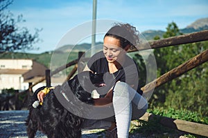 Happy woman stroking her dog, a black cocker spaniel while walking together in the nature
