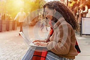 Happy woman student e-learning distance training course study working on stairs in the city. African Ethnicity young woman