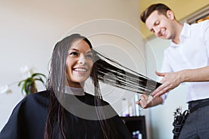 Happy woman with stylist cutting hair at salon