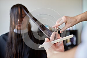 Happy woman with stylist cutting hair at salon