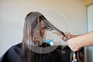 Happy woman with stylist cutting hair at salon