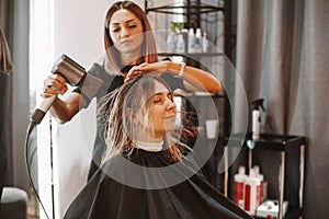 Happy woman with stylist making hairdo at salon