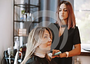 Happy woman with stylist making hairdo at salon