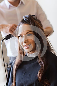 Happy woman with stylist making hairdo at salon