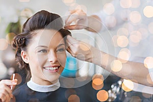 Happy woman with stylist making hairdo at salon