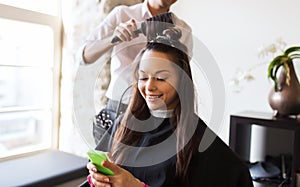 Happy woman with stylist making hairdo at salon