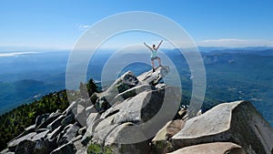 Happy woman in sucessfull pose on mountain top with scenic views.