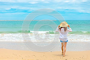 Happy Woman in summer vacation wearing hat and dress enjoying the view at the island beach