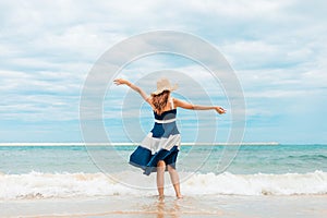 Happy Woman in summer vacation wearing hat and dress enjoying the view at the island beach