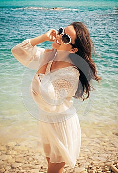 Happy woman in summer white dress on beach.