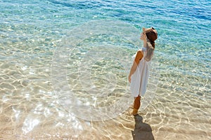 Happy woman in summer white dress on beach. girl relaxing and enjoying peace on vacation